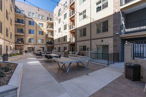 A courtyard with tables and chairs surrounded by apartment buildings. at The Revival, Salt Lake City